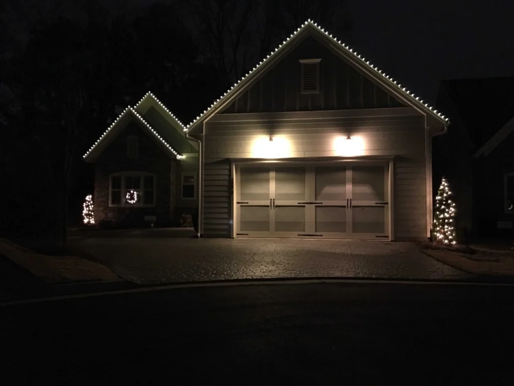Dark home at night with warm white Christmas lights tracing the roofline and garage
