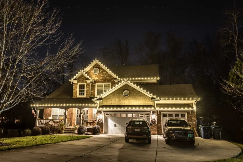 Traditional home with warm white Christmas lights tracing gables and garage rooflines
