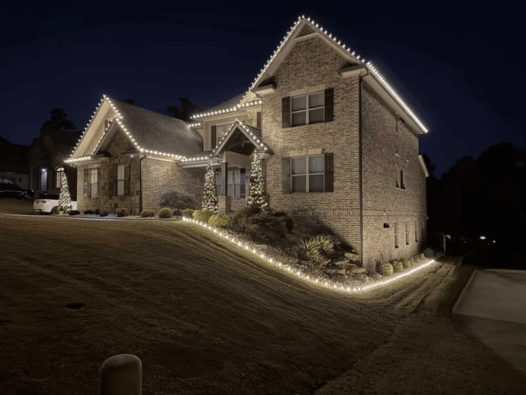 Home with warm white roofline Christmas lights and low walkway lighting along the front path