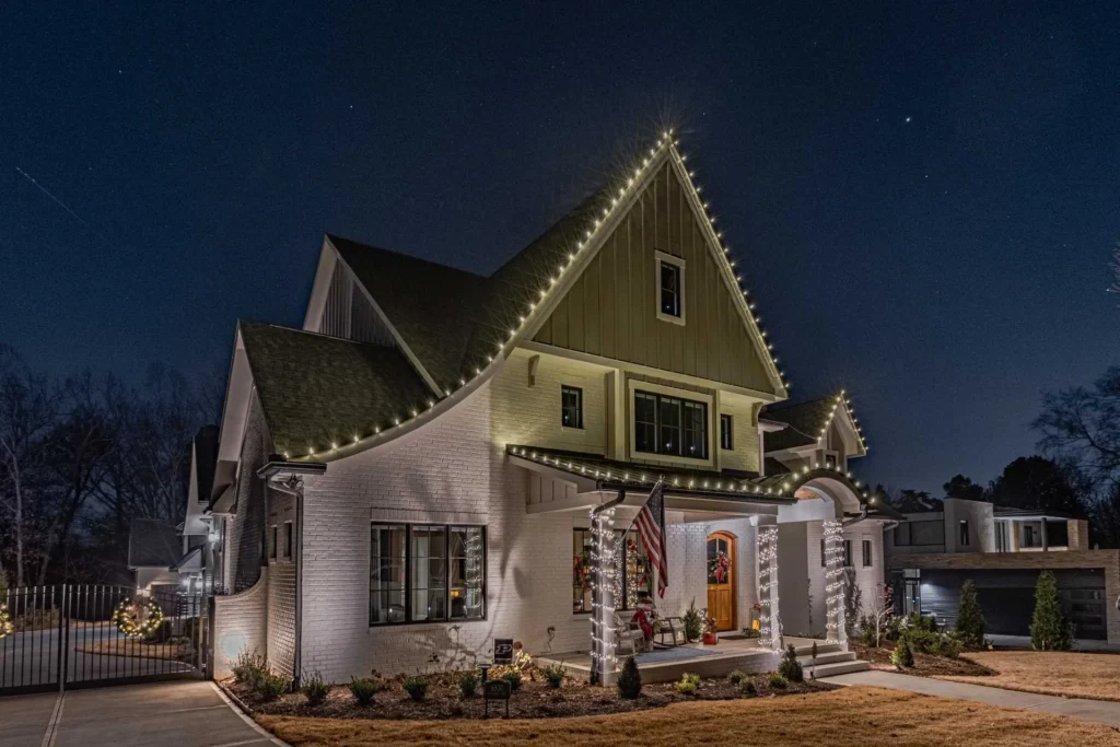 Home with warm white roofline Christmas lights and garland accents around the entry