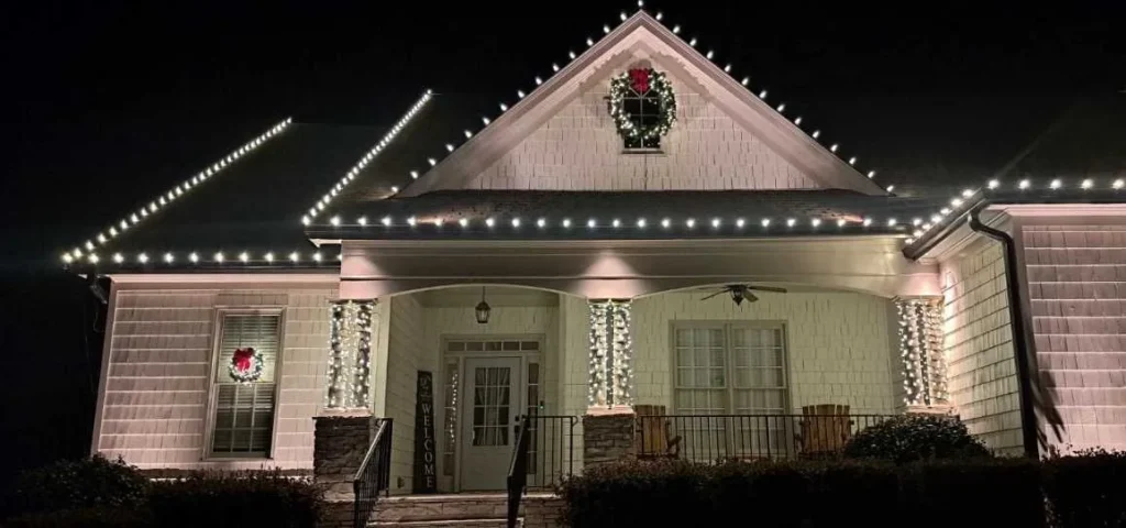 Single-story home with warm white roofline Christmas lights and a wreath on the front gable