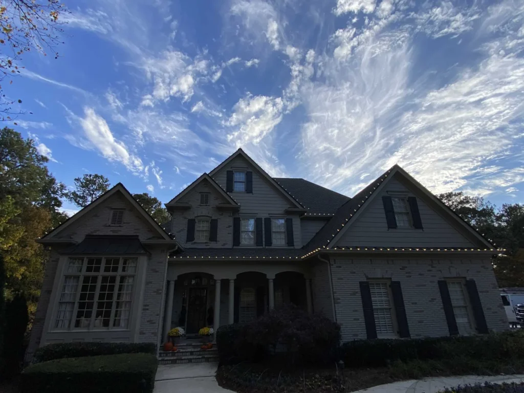 Daytime front view of a large home with multiple roof peaks and columns ready for holiday lighting design