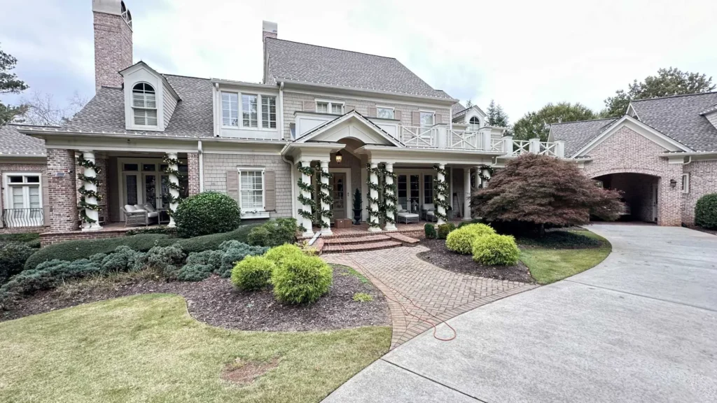 Daytime residential exterior with porch, rooflines, driveway, and landscaped front yard